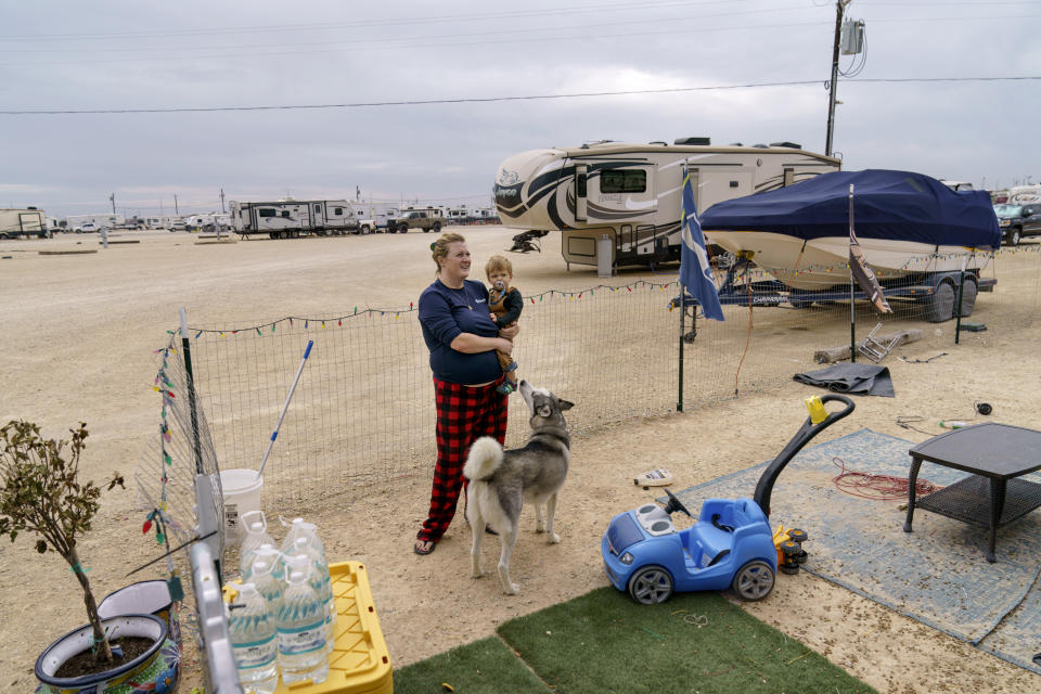 Tristan Yperman, 37, holds her son, Grant, 1, in the makeshift yard outside their RV at the Ocean Front RV Resort in Kermit, Texas, Oct. 13, 2021. Yperman’s husband is an engineer with a construction contractor widening the highway into Kermit, a sleepy desert crossroads that has seen its population grow with the oil boom. They have been living in their RV they’ve named Freya for about a year and move around as his job dictates. Spots in the 291 space RV park go for $780 a month, $1,200 for a small one-room cabin. “We never really know where we go next,” said Yperman who is expecting their second child in March. (AP Photo/David Goldman)