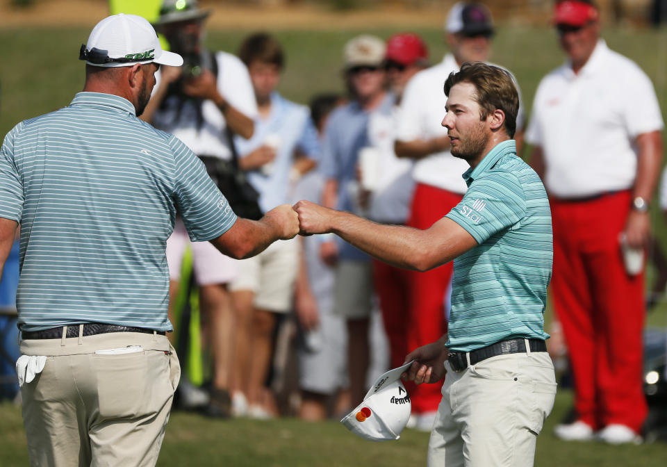 Marc Leishman, left, and Sam Burns, right, fist-bump on the 18th green following their second round of the AT&T Byron Nelson golf tournament in McKinney, Texas, Friday, May 14, 2021. (AP Photo/Ray Carlin)