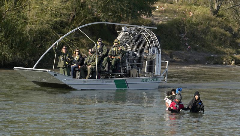 Border patrol agents watch as migrants cross the Rio Grande at the Texas-Mexico border, Wednesday, Jan. 3, 2024, in Eagle Pass, Texas.