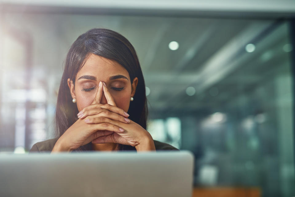 Shot of a young businesswoman looking stressed out while working in an office