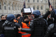 A striking train worker holds a box to collect -funds for striking workers in front of riot police officers outside the the Gare de Lyon train station, Monday, Dec. 23, 2019 in Paris. A wildcat protest comes on Day 19 of nationwide strike over the government's plans to raise the retirement age to 64. The union-led protest Monday led to a standoff with riot police that spilled onto the streets around the historic Gare de Lyon train station. (AP Photo/Francois Mori)