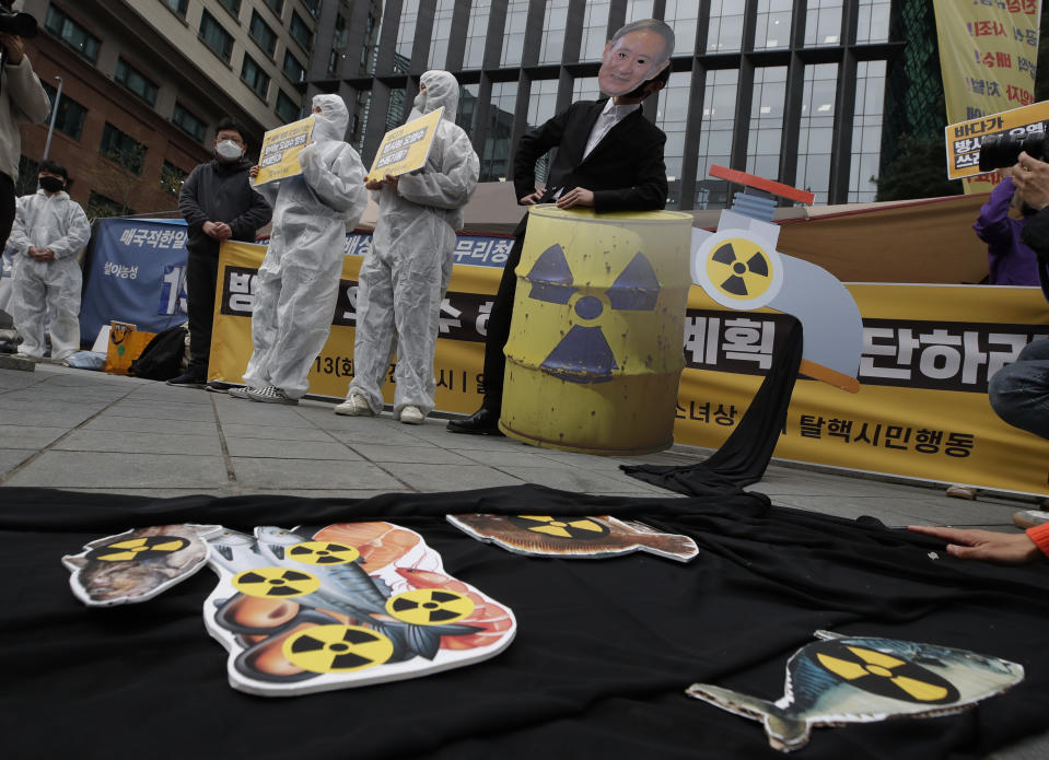 Environmental activists wearing a mask of Japanese Prime Minister Yoshihide Suga and protective suits perform to denounce the Japanese government's decision on Fukushima water, near the Japanese embassy in Seoul, South Korea, Tuesday, April 13, 2021. Japan's government decided Tuesday to start releasing massive amounts of treated radioactive water from the wrecked Fukushima nuclear plant into the Pacific Ocean in two years - an option fiercely opposed by local fishermen and residents. (AP Photo/Lee Jin-man)