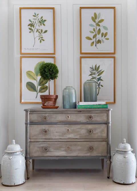 Framed botanical prints flank a vintage chest.