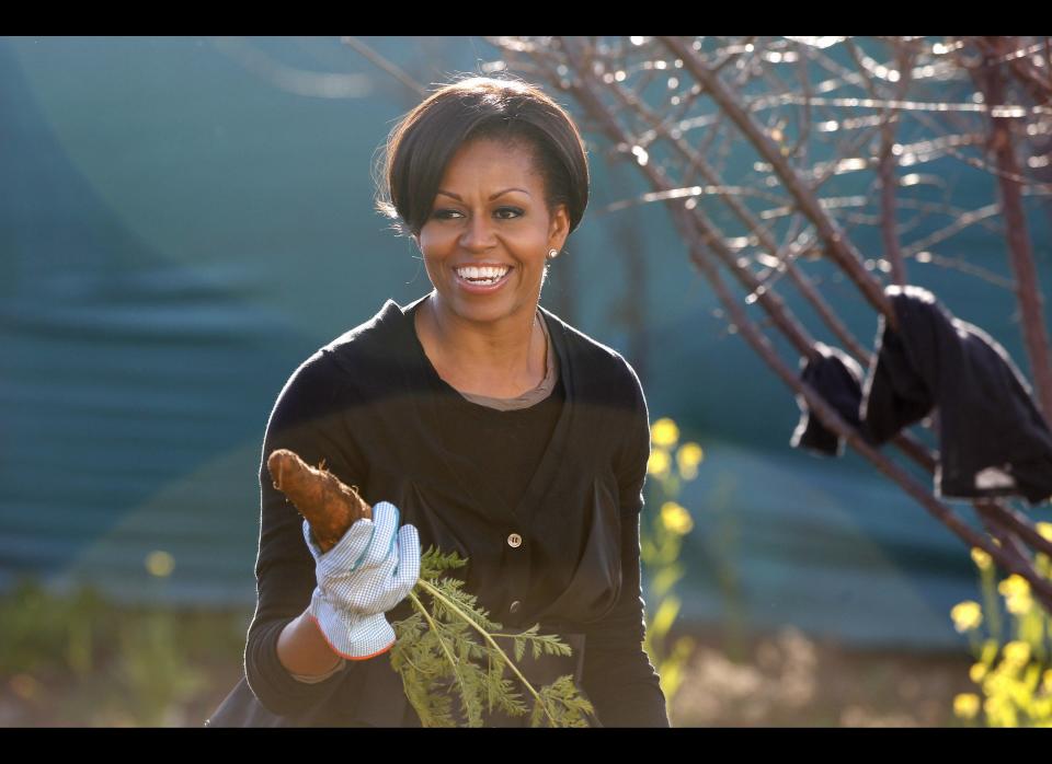 US First Lady Michelle Obama holds up a carrot as she gardens during  a community service project at Vhuthilo Community Center in Soweto township, Johannesburg, South Africa, June 22, 2011. AFP PHOTO /Charles Dharapak / POOL (Photo credit should read CHARLES DHARAPAK/AFP/Getty Images)