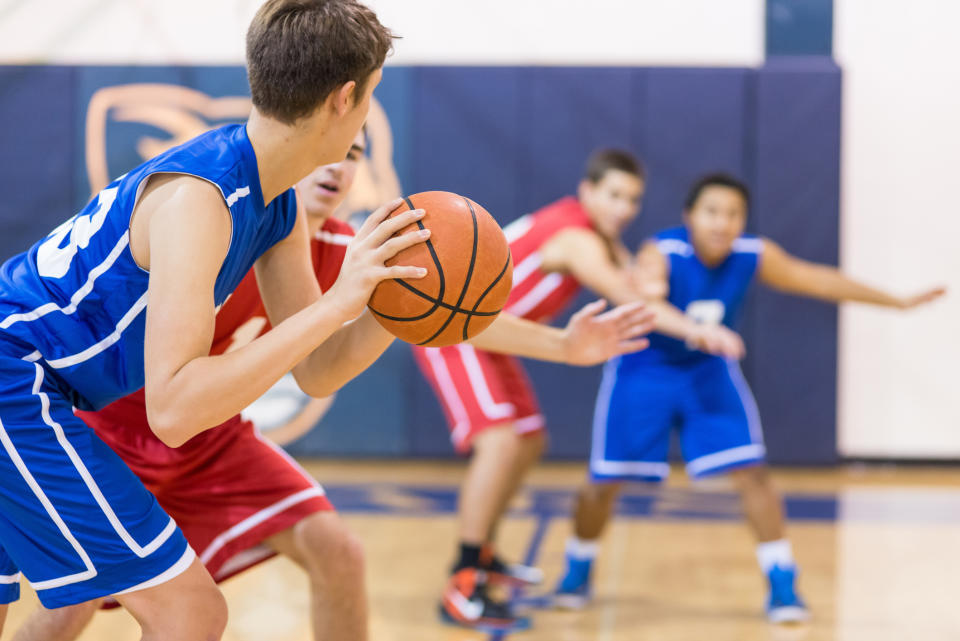 Teen basketball players in action during a game on an indoor court