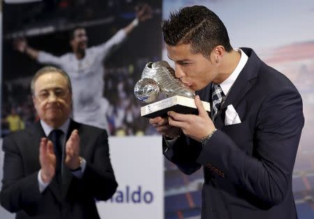Real Madrid's Cristiano Ronaldo (R) kisses a trophy as club's president Florentino Perez applauds during a ceremony at Santiago Bernabeu stadium in Madrid, Spain October 2, 2015. REUTERS/Sergio Perez