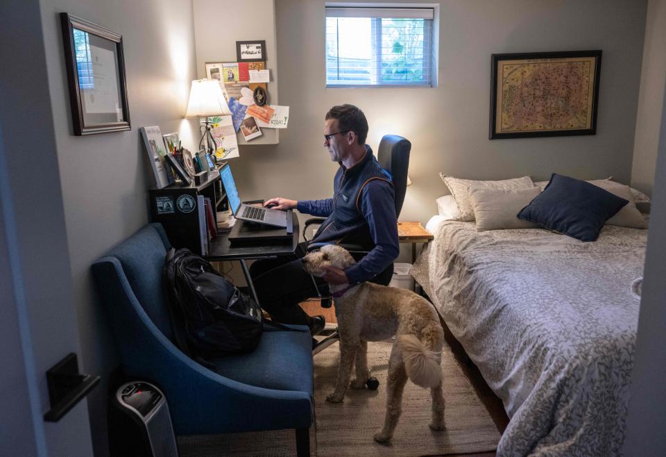 Danny Crouch pets his dog as he works from home in Arlington, Va.