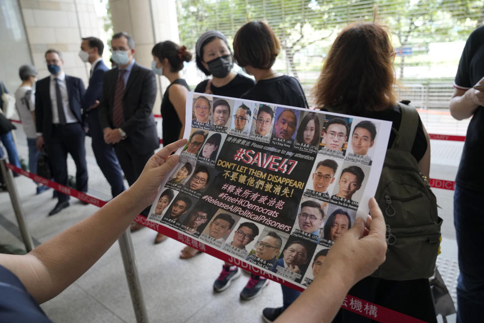 A supporter holds a placard with the photos of some of the 47 pro-democracy defendants outside a court in Hong Kong, Thursday, July 8, 2021. A court hearing for 47 pro-democracy activists charged with conspiracy to commit subversion under the security law over their involvement in an unofficial primary election last year that authorities said was a plot to paralyze Hong Kong's government. (AP Photo/Kin Cheung)