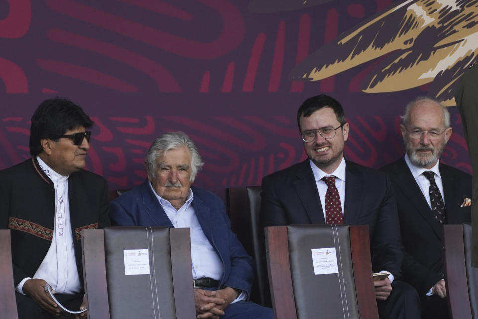 Uruguay's former President Jose Mujica, second from left, Bolivia's former President Evo Morales, left, and the brother and father of Julian Assange, John Shipton and Gabriel Shipton, attend Mexico's annual Independence Day military parade at the main square, the Zocalo, in Mexico City, Friday, Sept. 16, 2022. (AP Photo/Marco Ugarte)