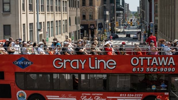 People ride a tourist bus through downtown Ottawa earlier this summer during the COVID-19 pandemic. (Brian Morris/CBC - image credit)