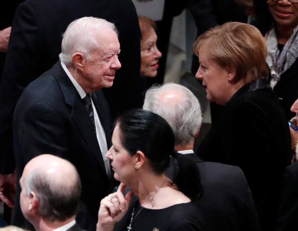 Former United States President Jimmy Carter talks with German Chancellor Angela Merkel as they arrive for the funeral services for former United States President George H. W. Bush at the National Cathedral, in Washington, DC on Dec. 5, 2018.