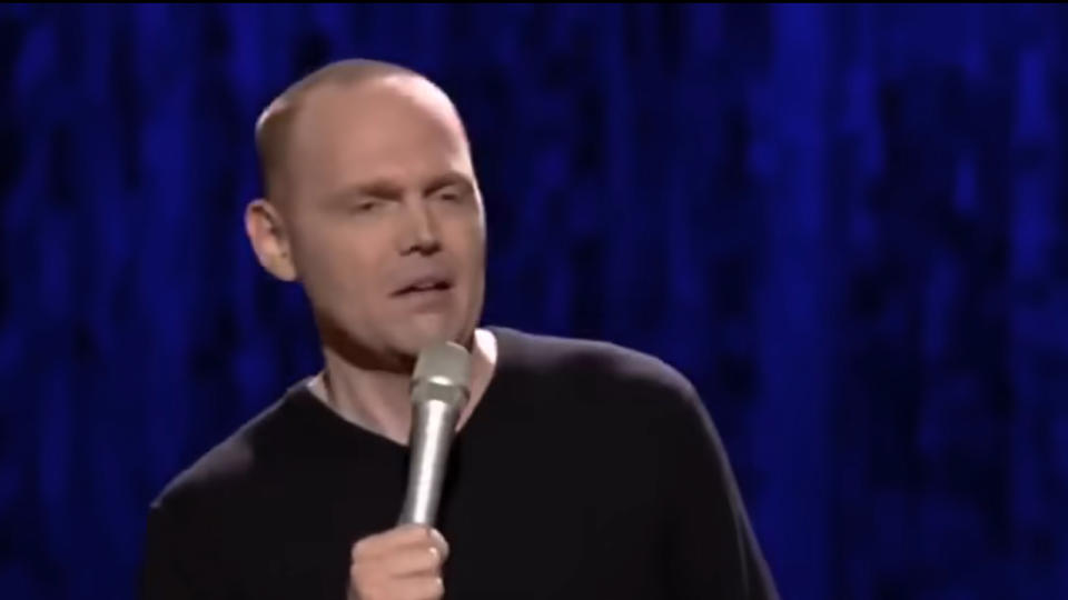 Bill Burr holding a microphone and looking annoyed
