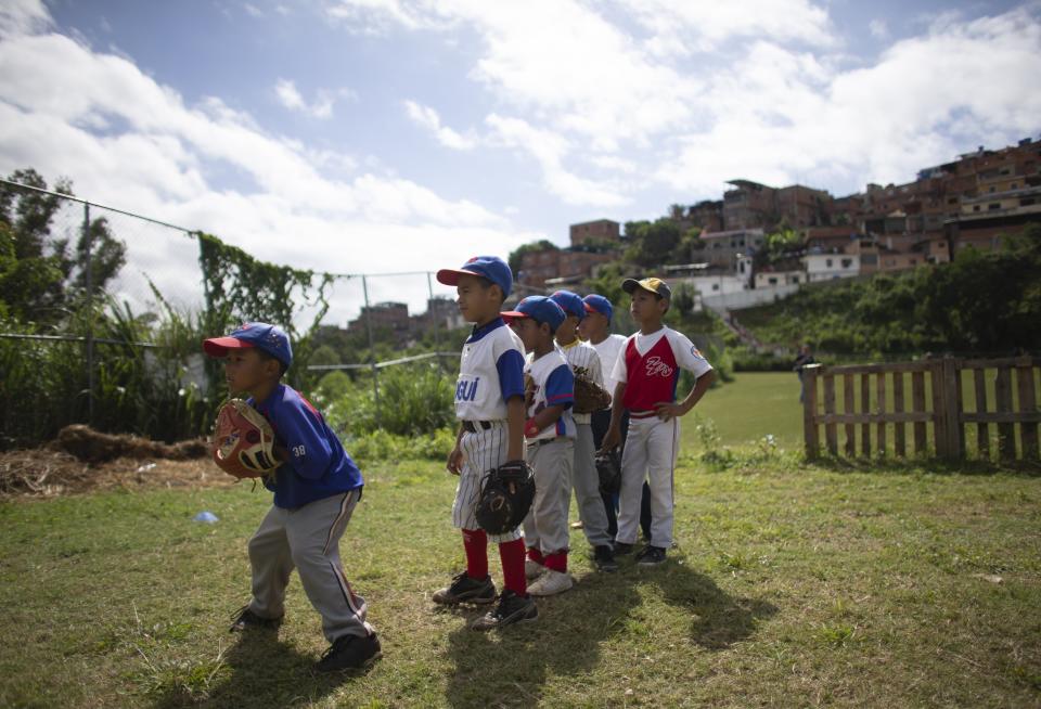 In this Aug. 12, 2019 photo, a young baseball player prepares to catch a ball during a practice at Las Brisas de Petare Sports Center, in Caracas, Venezuela. More than 100 boys train daily on the baseball field using old bats, balls and gloves, in hopes of achieving a professional baseball career in the United States. (AP Photo/Ariana Cubillos)