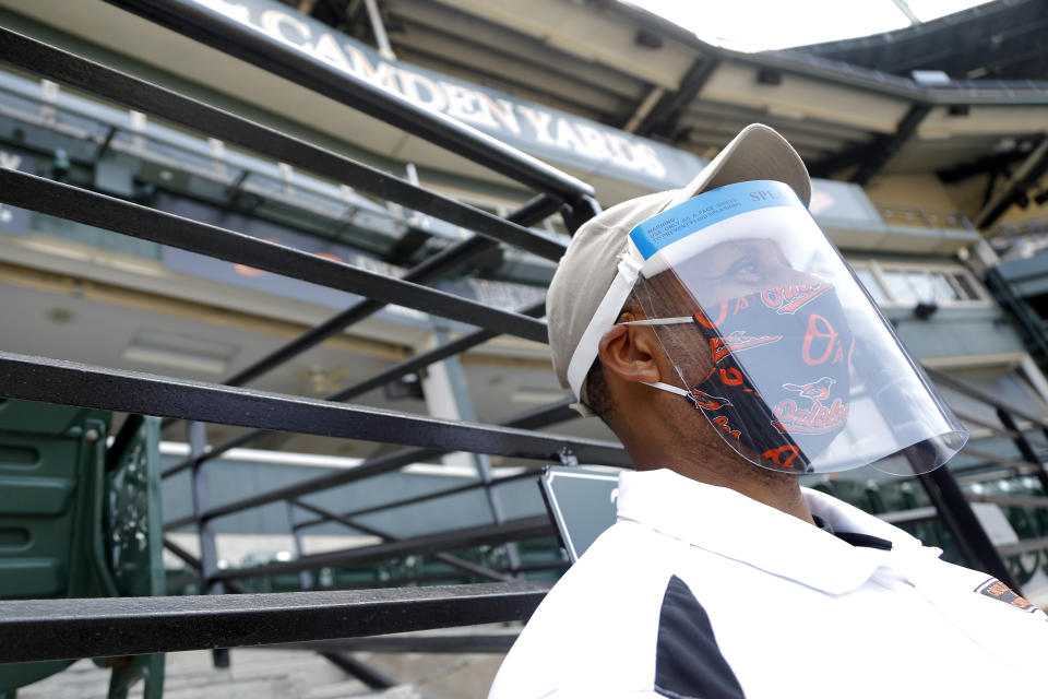 A security officer uses a face mask and shield to protect against the new coronavirus while assisting at Baltimore Orioles baseball training camp, Friday, July 3, 2020, in Baltimore. (AP Photo/Julio Cortez)