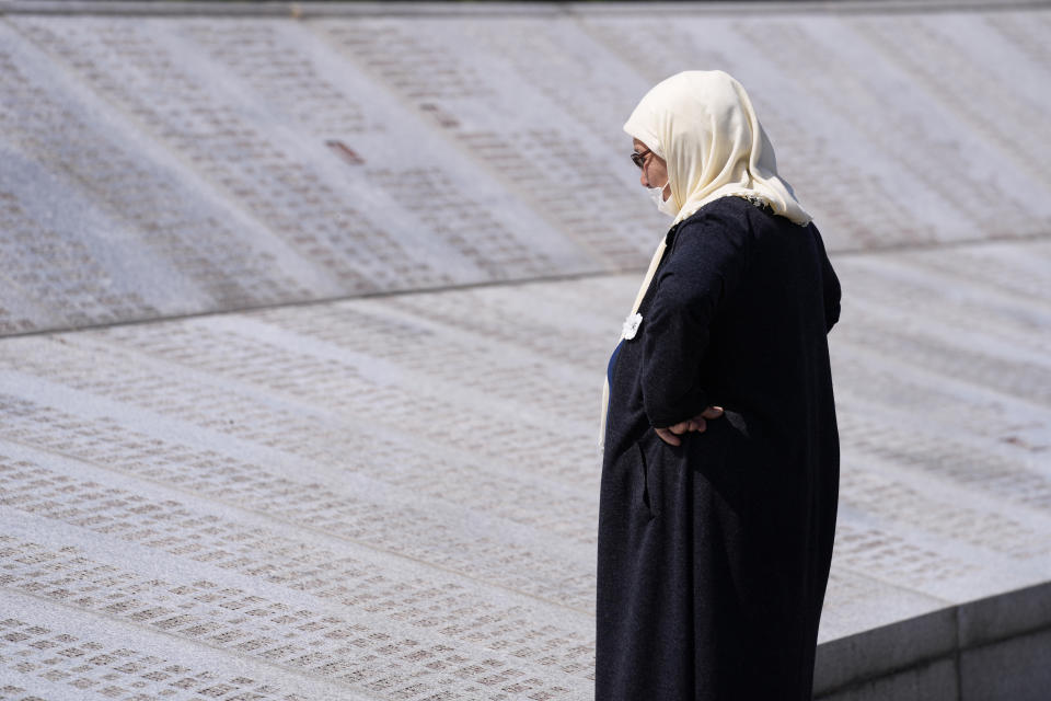 FILE - Djulija Jusic, who lost two sons and thirty three other relatives in the Srebrenica massacre, looks at the names at the memorial cemetery in Potocari, near Srebrenica, eastern Bosnia, Tuesday, June 8, 2021. Survivors of war crimes committed during Bosnia’s 1992-95 war say the victims of ongoing human rights abuses in Ukraine should learn from their experience of fighting for justice, but that they must first make peace with the fact that reaching it will inevitably be a lengthy and painful process. It took decades to arrest and try the wartime Bosnian Serb leaders, and three decades since the start of that war more than 7,000 people remain unaccounted-for. (AP Photo/Darko Bandic, File)
