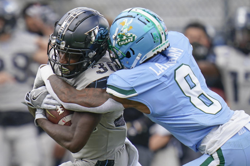 Central Florida running back Greg McCrae, left, is tackled by Tulane cornerback Willie Langham (8) after a gain during the first half of an NCAA college football game, Saturday, Oct. 24, 2020, in Orlando, Fla. (AP Photo/John Raoux)