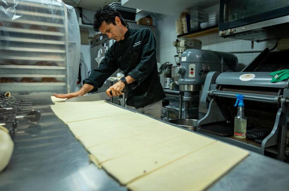Yusel Montelongo cuts the layered dough to make croissants in the kitchen at L’Boulanger Maison du Croissant.