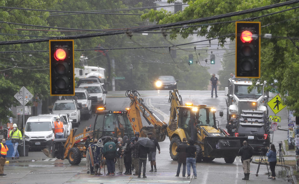 Seattle Department of Transportation workers remove barricades at the intersection of 10th Ave. and Pine St., Tuesday, June 30, 2020 at the CHOP (Capitol Hill Occupied Protest) zone in Seattle. Protesters quickly moved couches, trash cans and other materials in to replace the cleared barricades. The area has been occupied by protesters since Seattle Police pulled back from their East Precinct building following violent clashes with demonstrators earlier in the month. (AP Photo/Ted S. Warren)