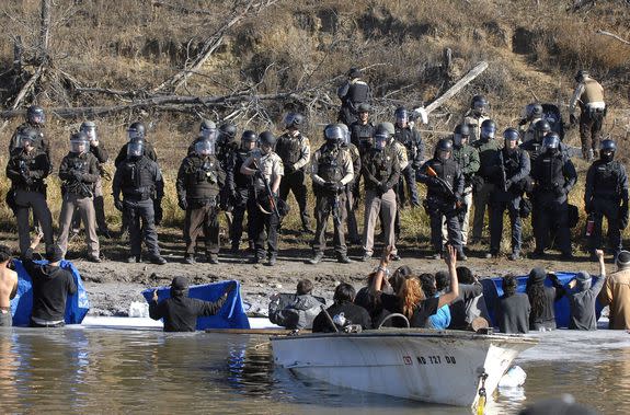 Pipeline protesters face officers in riot gear in the Cantapeta Creek, near Cannon Ball.