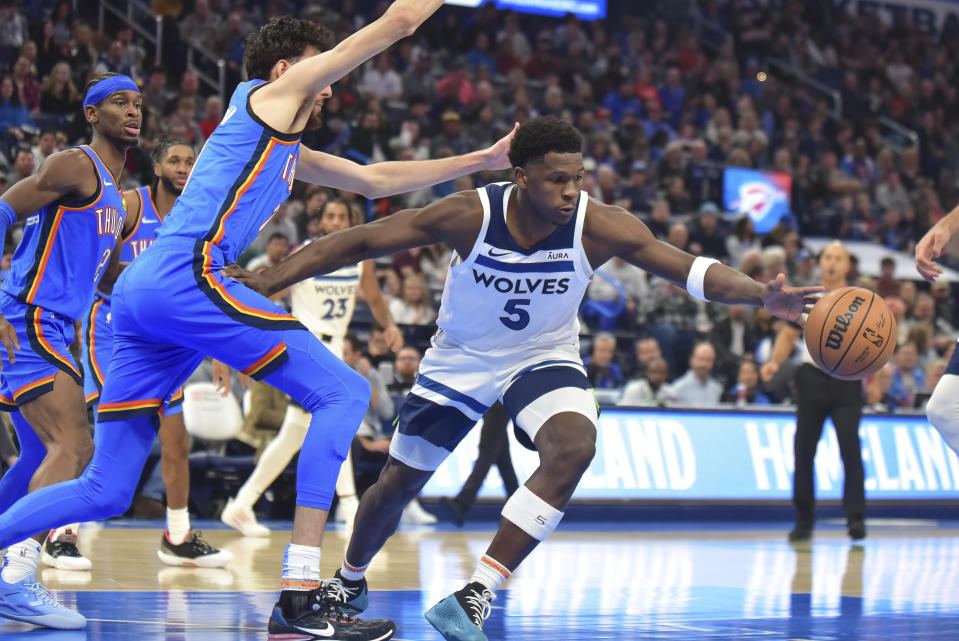 Minnesota Timberwolves guard Anthony Edwards, right, loses the ball as he tries to get past Oklahoma City Thunder forward Chet Holmgren, left, during the first half of an NBA basketball game Tuesday, Dec. 26, 2023, in Oklahoma City. (AP Photo/Kyle Phillips)