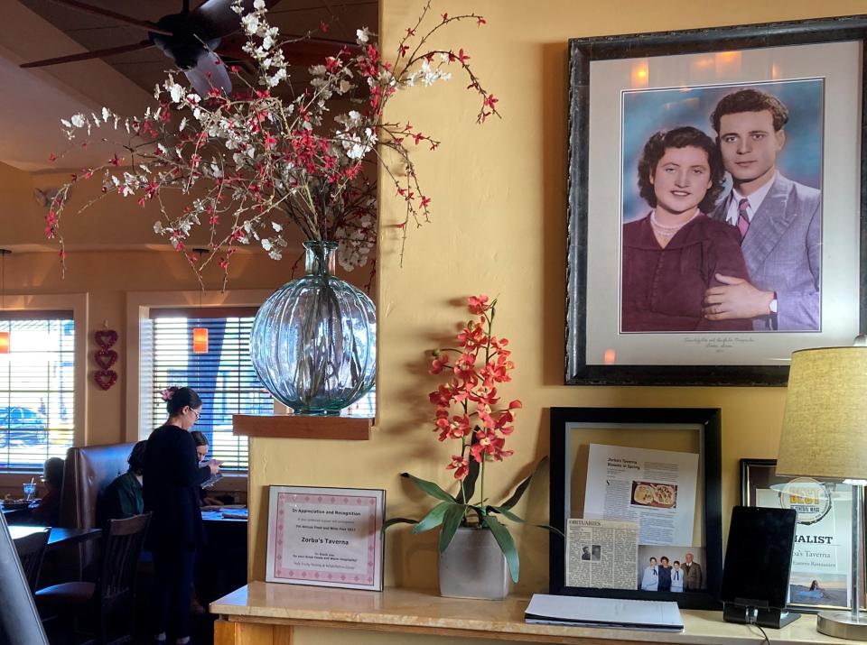 The entrance to Zorba's Taverna on Stafford Street in Worcester boasts a portrait of former area restaurateurs and the in-laws of Nusa Dimopoulos. Server Valerie Queirolo attends customers in the background on Feb. 3, the restaurant's last day.