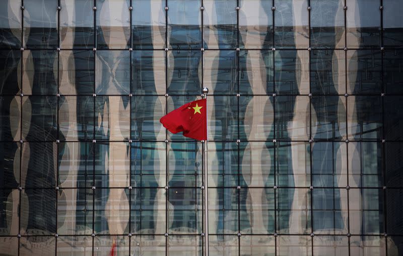 FILE PHOTO: Chinese national flag flutters at the headquarters of a commercial bank on a financial street near the headquarters of the People's Bank of China, China's central bank, in central Beijing