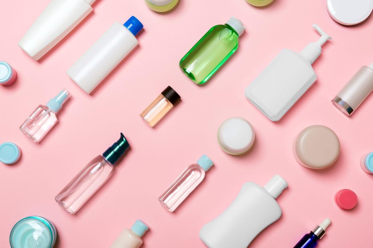 Top view of different cosmetic bottles and container for cosmetics on pink background. Flat lay composition with copy space