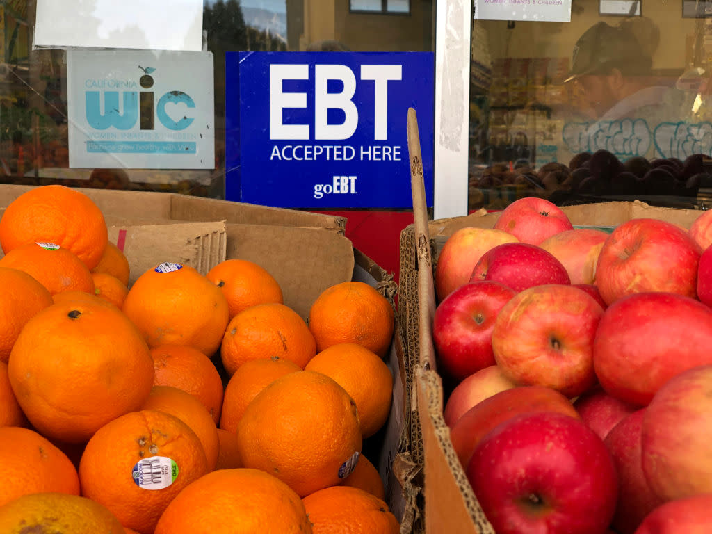 A box of oranges and a box of fruit with a sign saying EBT behind them.