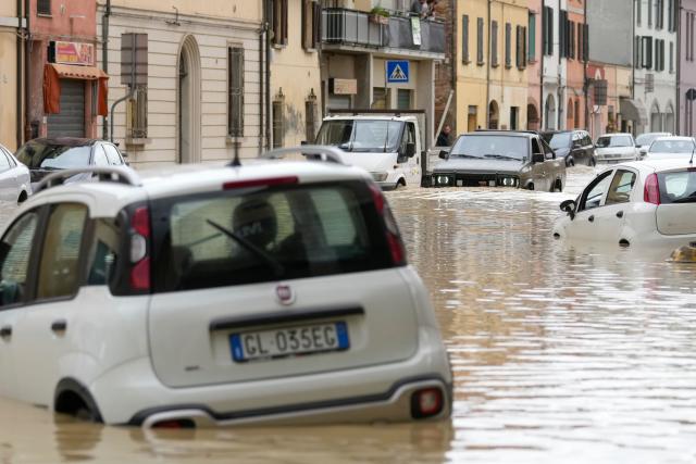 Cars are partially submerged along a flooded street in Castel Bolognese. (AP)
