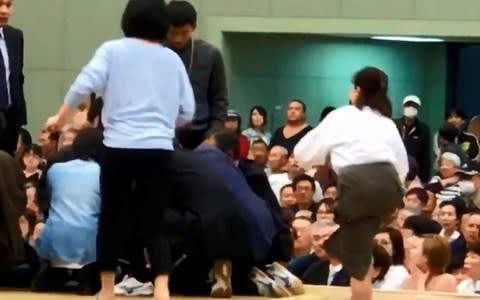 A photo grab from a Youtube video shows women climbing up a sumo ring to treat Maizuru city mayor Ryozo Tatami - Credit: Kyodo via Reuters