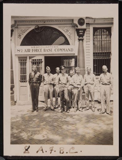A photograph of a group of servicemen standing in front of the building headquarters for the United States Eighth Air Force Base Command in Savannah, Georgia. A sign on the building reads "Headquarters Eighth Air Force Base Command." The back of the photograph reads: "Early 1942 Savannah Ga." In England, on 27 May 1942 Eighth Air Force Base Command was redesignated VIII Air Force Service Command.