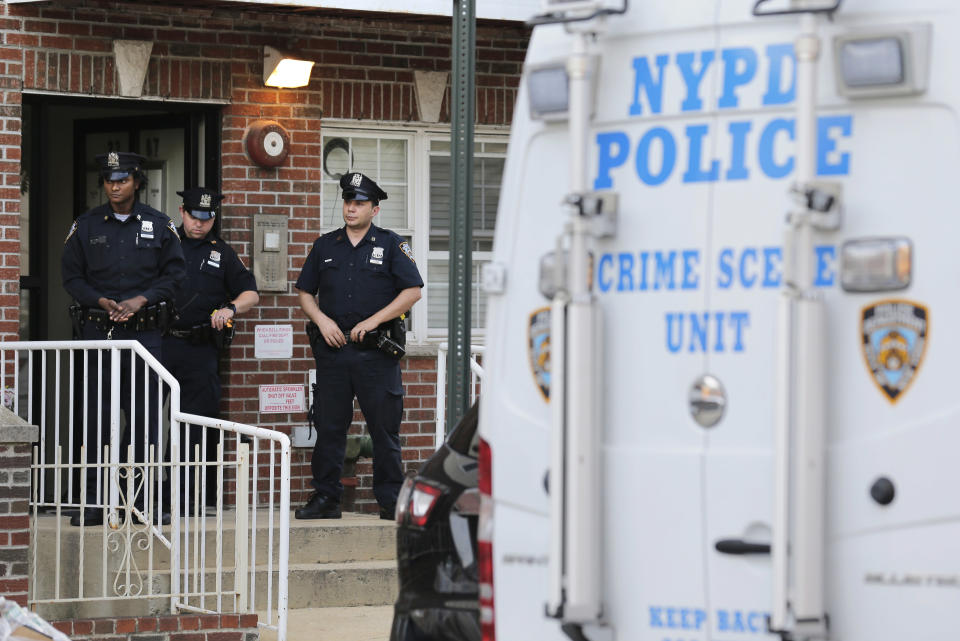 Police officers stand in front of a building where there was a shooting with multiple fatalities in the Queens borough of New York, Tuesday, July 31, 2018. (AP Photo/Seth Wenig)