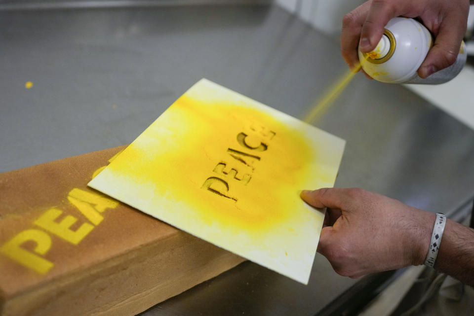 Baker Matteo Cunsolo prepares the 'bread for peace' in his laboratory in Parabiago near Milan in northern Italy, Thursday, March 17, 2022. Cunsolo used saffron and the infusion of a Thai plant to make a bicolor loaf of bread with the colors of the Ukraine national flag and butter-sprayed the word 'peace' on its sides in solidarity with the war-battered country. (AP Photo/Luca Bruno)