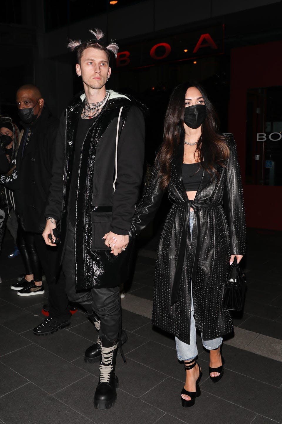 <p>Fox tied a long black leather coat over her black bralette, jeans and black heels, teamed with a black face mask while out with her partner. </p>