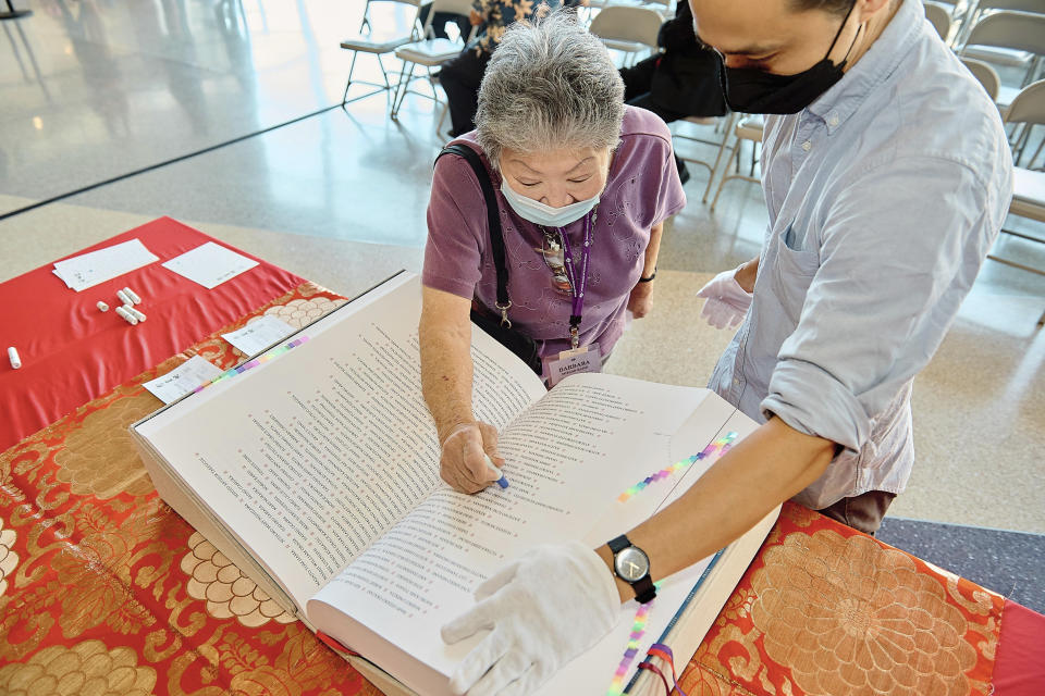 In this photo provided by the Japanese American National Museum, Barbara Keimi stamps the Ireichō at the Japanese American National Museum in Los Angeles on Sept. 24, 2022. The book lists the names of the more than 125,000 people who were detained in internment camps for Japanese Americans nationwide during World War II. Visitors are encouraged to look for their loved ones in the Ireichō and leave a mark under their names using a Japanese stamp called a hanko. (Mike Palma/JANM via AP)