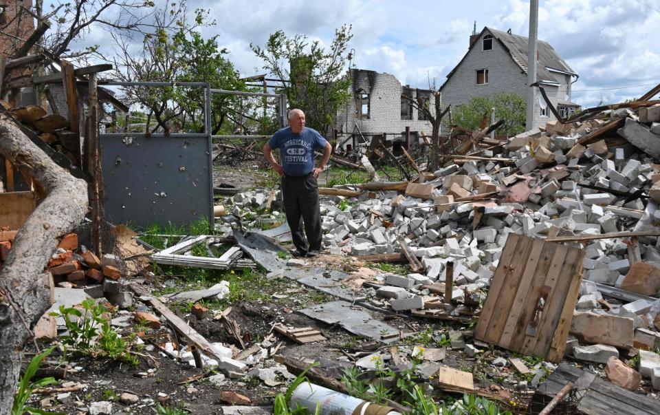 A local resident stand among debris in a yard of his destroyed house in the village of Mala Rogan, east of Kharkiv - SERGEY BOBOK 