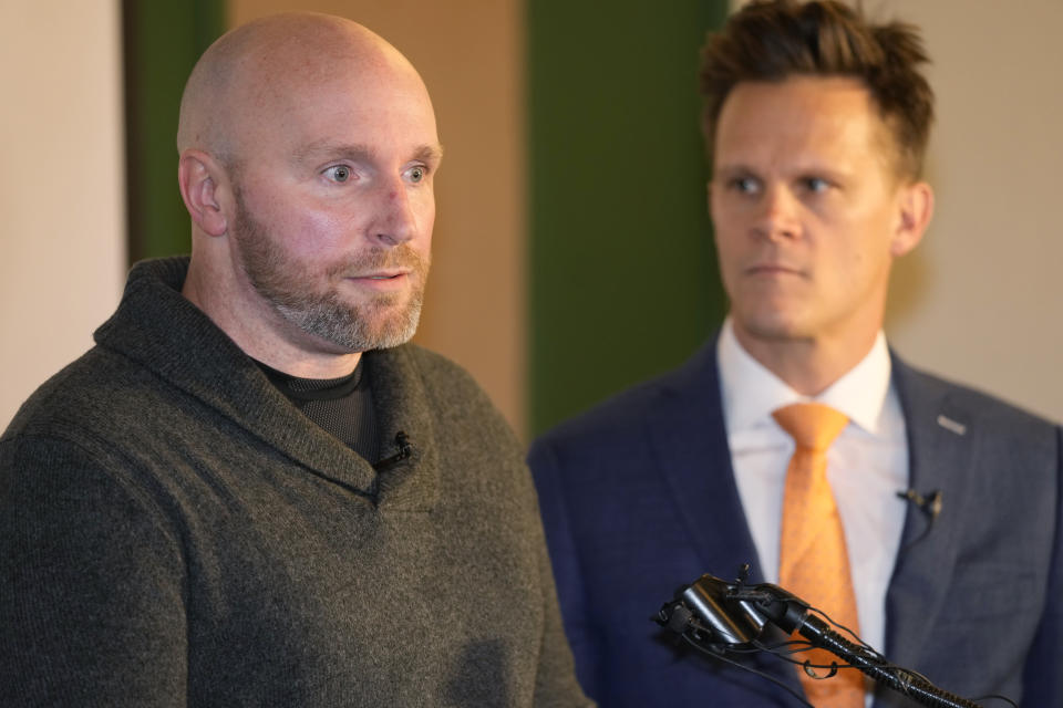 Scott Verti, front, responds to questions during a news conference ast the Denver Press Club on Thursday, Jan. 19, 2023, in Denver. Verti, who says he was repeatedly sexually abused as a teenager by a Catholic priest while serving as an altar boy in a parish in Fort Collins, Colo., is suing that defrocked priest and the Archdiocese of Denver. Verti's lawyer, Kurt Zaner, back, looks on. (AP Photo/David Zalubowski)