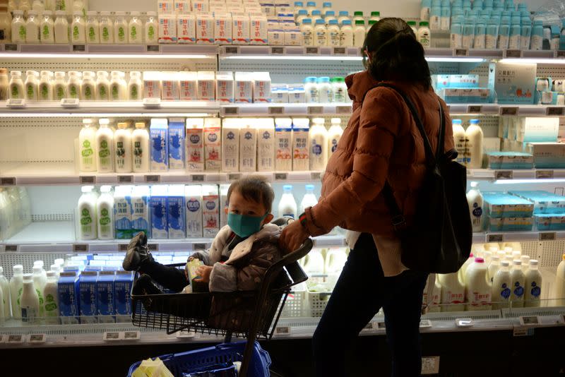 Woman shops as she pushes a trolley with a boy wearing a mask at a supermarket, as the country is hit by an outbreak of the new coronavirus, in Beijing