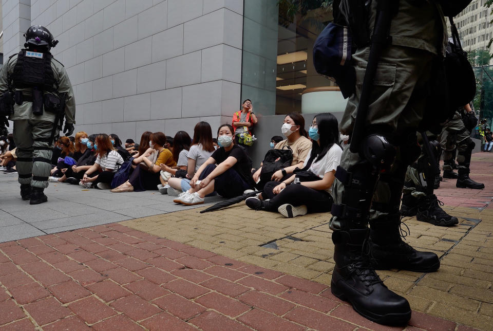 Riot police guard arrested anti-government protesters in the Causeway Bay district of Hong Kong, Wednesday, May 27, 2020. Hong Kong police massed outside the legislature complex Wednesday, ahead of debate on a bill that would criminalize abuse of the Chinese national anthem in the semi-autonomous city. (AP Photo/Vincent Yu)