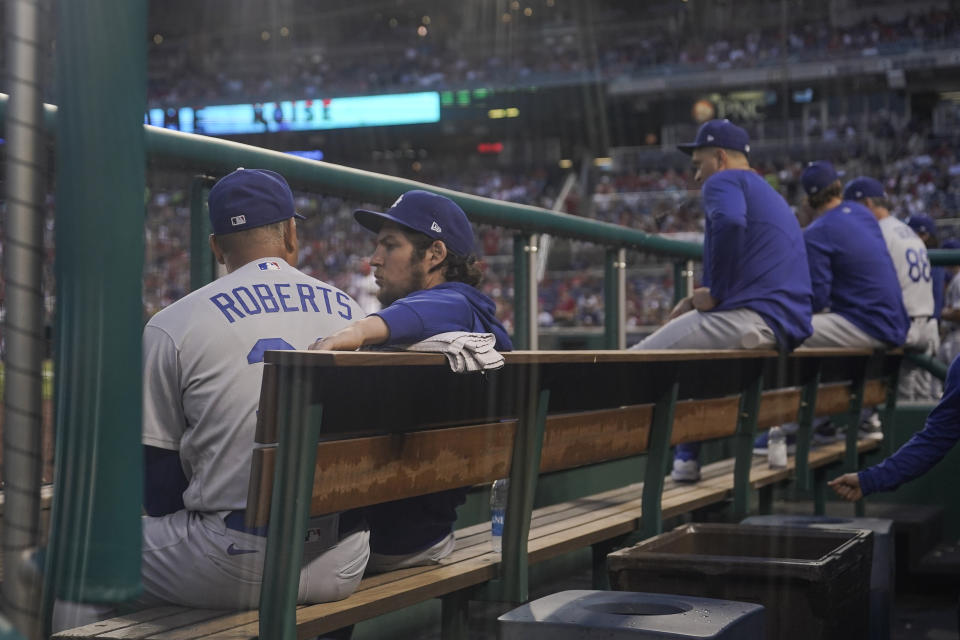 Los Angeles Dodgers manager Dave Roberts, left, talks with starting pitcher Trevor Bauer in the dugout during the fourth inning of a baseball game against the Washington Nationals, Thursday, July 1, 2021, in Washington. (AP Photo/Julio Cortez)