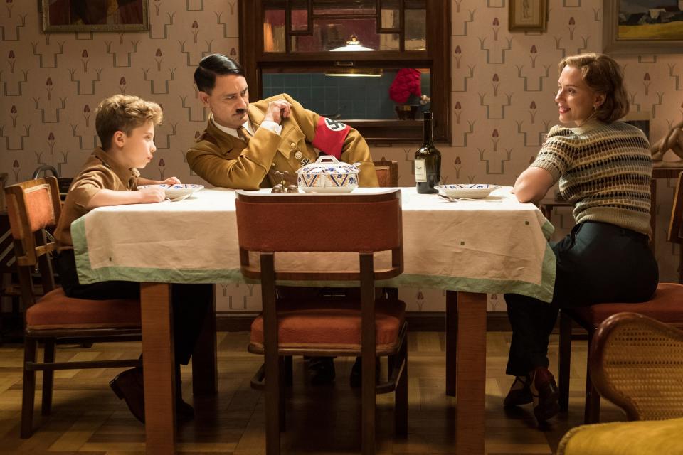 Jojo (Roman Griffin Davis) has dinner with his imaginary friend Adolf (Taika Waititi) and his mother Rosie (Scarlett Johansson) in the World War II satire "Jojo Rabbit."