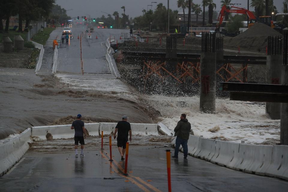 People check out the waters from Tropical Storm Hilary on Sunday as they flow through the Whitewater River at Dune Palms Road near La Quinta High School. The road is currently under construction and a new bridge is being built.