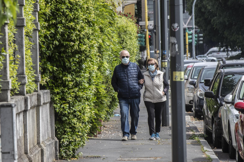 FILE - In this photo taken on Thursday, April 30, 2020, a couple walk arm in arm, in Milan, Italy, Thursday, April 30, 2020. Under Italy’s more relaxed lockdown rules starting next week, people can visit family within the same region. But confusion abounds over how close the family connection needs to be. Does a second cousin qualify? A third? A sister-in-law’s kids? When asked to clarify Prime Minister Conte muddied the water even more, saying those with relations of ‘stable affection’ would qualify. That left Italians wondering whether girlfriends or boyfriends would pass the test. (AP Photo/Luca Bruno)