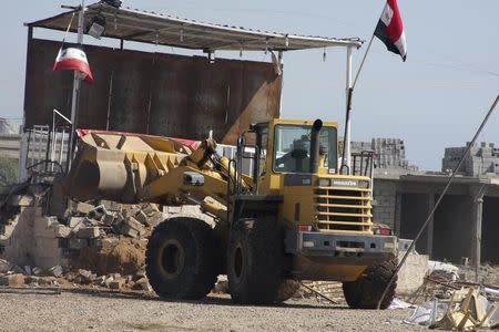 A platform at a makeshift camp is removed by heavy equipment at a public square in Hawija, near Kirkuk, 170 km (100 miles) north of Baghdad April 23, 2013. REUTERS/Stringer