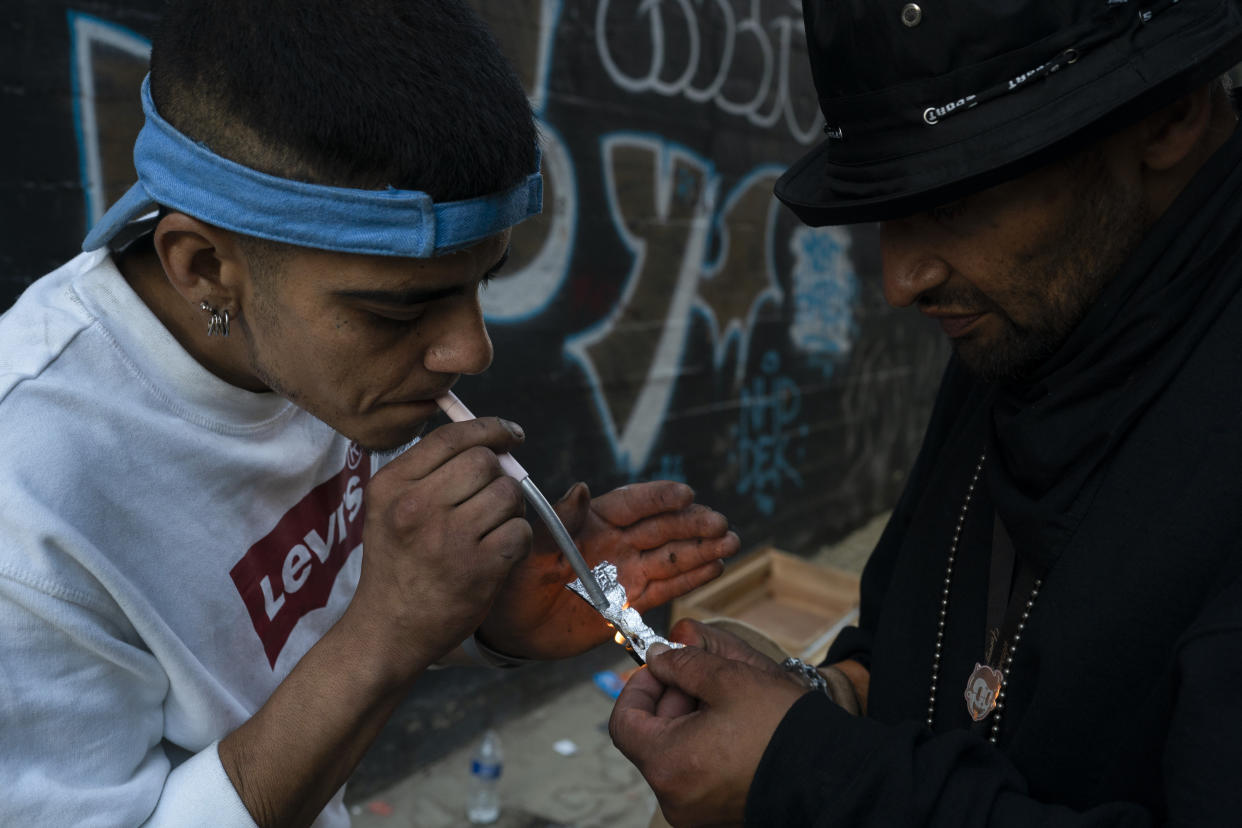 Two homeless addicts share a small piece of fentanyl in an alley in Los Angeles, Thursday, Aug. 18, 2022. Use of fentanyl, a powerful synthetic opioid that is cheap to produce and is often sold as is or laced in other drugs, has exploded. Two-thirds of the 107,000 overdose deaths in 2021 were attributed to synthetic opioids like fentanyl, the U.S. Centers for Disease Control and Prevention says. (AP Photo/Jae C. Hong)