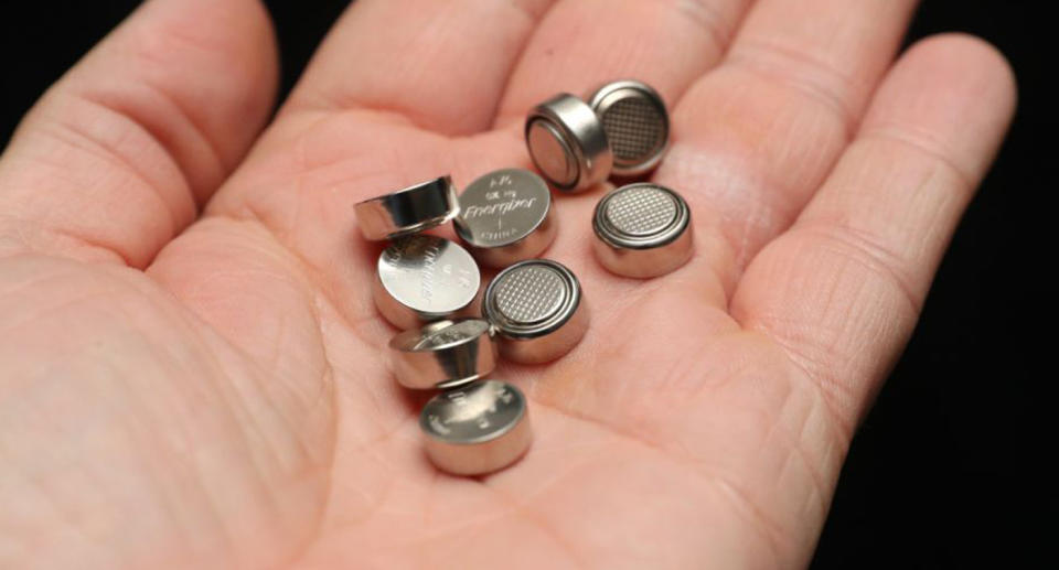 A person holds a pile of Energizer LR44/A76 Alkaline 1.5v batteries in their hand.