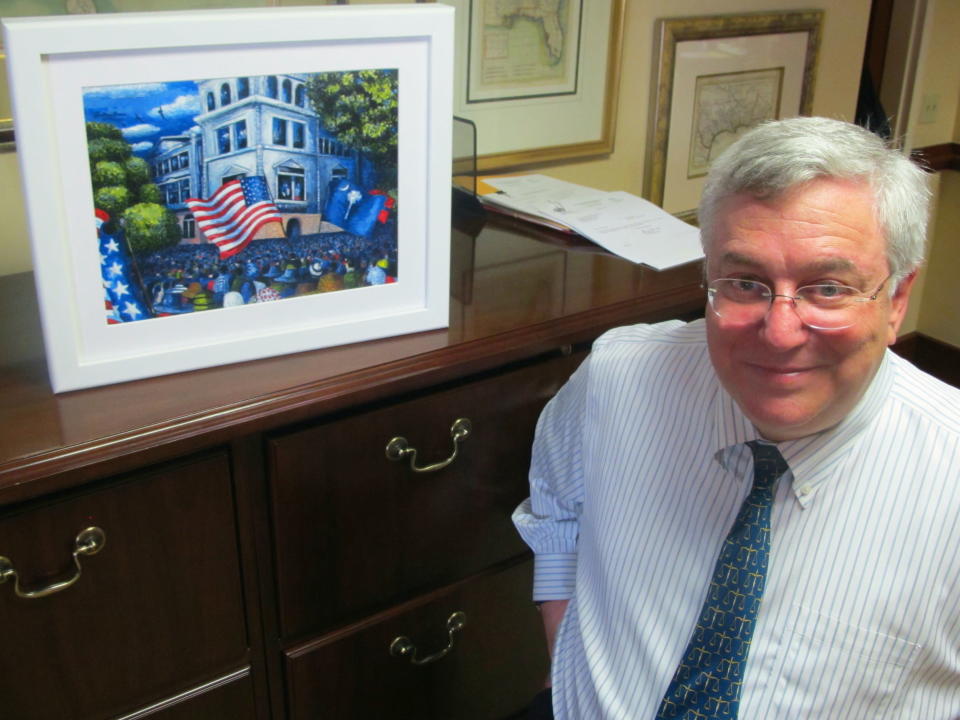 U.S. District Judge Richard Gergel poses in his office in the federal courthouse in Charleston, S.C., on Thursday, April 3, 2014 beside a painting by noted artist Jonathan Green. The painting depicts the outside of the courthouse in 1951 when three federal judges heard a school desegregation case from Clarendon County, S.C. A statue of U.S. District Judge Waites Waring, one of the judges in the case and who was the first to write an opinion that separate schools are not equal schools since separate but equal became the law of the land, is being dedicated outside the courthouse on April 11, 2014. (AP Photo/Bruce Smith)