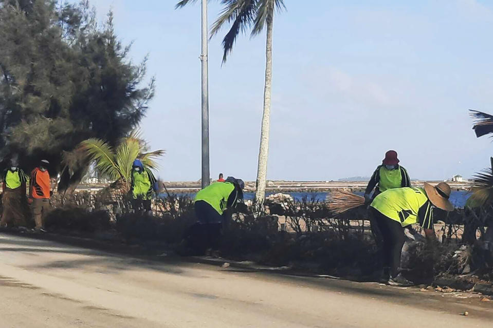 In this photo provided by Broadcom Broadcasting, people clear debris off the street in Nuku'alofa, Tonga, Thursday, Jan. 20, 2022, following Saturday's volcanic eruption near the Pacific archipelago. The first flight carrying fresh water and other aid to Tonga was finally able to leave Thursday after the Pacific nation's main airport runway was cleared of ash left by the eruption. (Marian Kupu/Broadcom Broadcasting via AP)