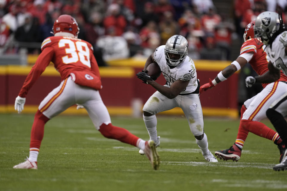 Las Vegas Raiders running back Zamir White (35) runs with the ball as Kansas City Chiefs cornerback L'Jarius Sneed (38) defends during the second half of an NFL football game Monday, Dec. 25, 2023, in Kansas City, Mo. (AP Photo/Charlie Riedel)