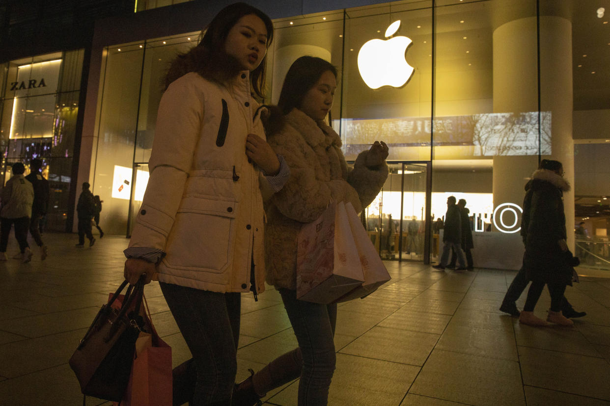 Shoppers walk past a store of US tech giant Apple in a retail district in Beijing on Friday, Dec. 13, 2019. China deputy trade envoy says China, U.S. have reached trade deal, will reduce punitive tariffs on each other's goods (AP Photo/Ng Han Guan)